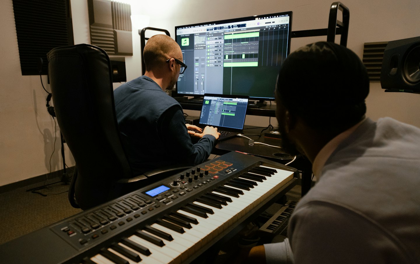 Due uomini che lavorano insieme in uno studio musicale con una tastiera MIDI.